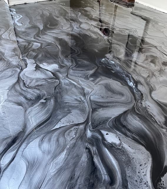 Glossy metallic epoxy floor with swirling patterns of silver, grey, and black marble-like textures.